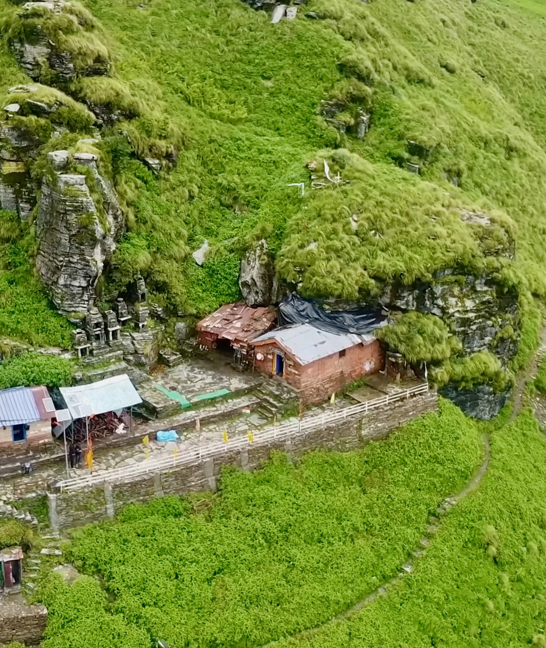 Luftaufnahme eines kleinen Dorfes umgeben von Grünflächen mit verstreuten Häusern und Text unten.