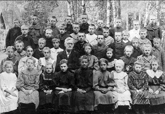 Schwarz-weißes Foto von Kindern, die vor einem Baumhintergrund posieren, mit dem Text "1930-1940 Russische Schule" unten.