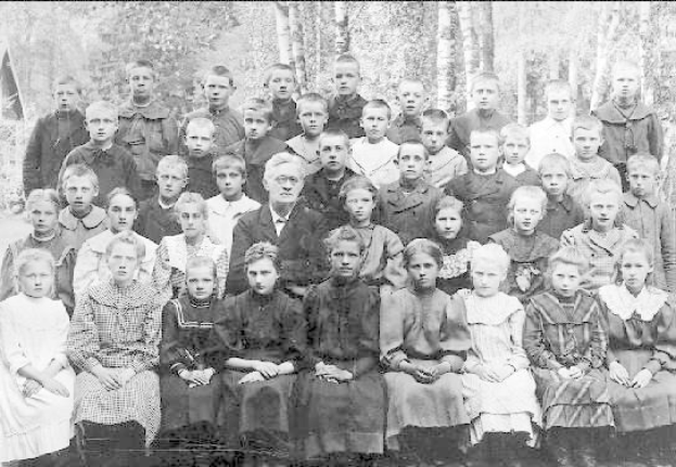 Schwarz-weißes Foto von Kindern, die vor einem Baumhintergrund posieren, mit dem Text "1930-1940 Russische Schule" unten.