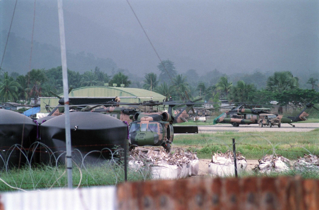 Eine Gruppe von Militärhubschraubern auf einem Rasen neben einem Zaun geparkt