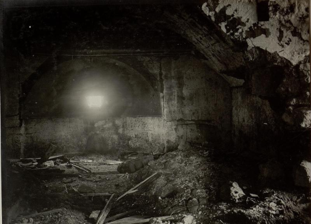 Altes Schwarz-Weiß-Foto eines zerfallenden Tunnels in den Berliner Mauerruinen, mit Schutt auf dem Boden und einem Licht am Ende.