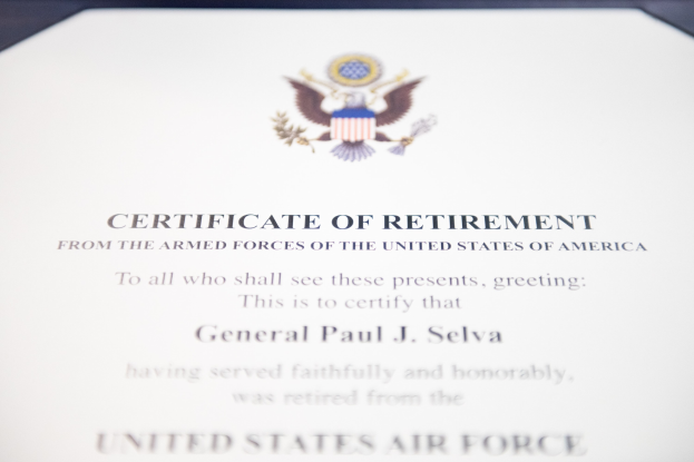 Blauer Rahmen mit einem Abschiedszeugnis der United States Air Force, das ein schwarzes Logo mit einem Stern und einem Lorbeerkranz sowie eine Banner mit der Aufschrift 'Ruhestand' zeigt.