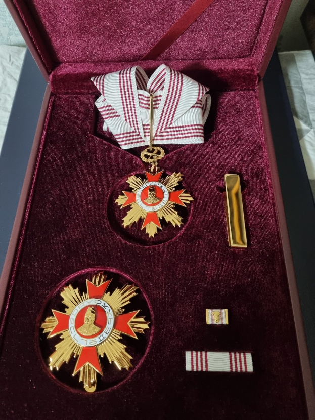 Roter Kasten mit der Medaille des Sterns des russischen Ordens mit einer weißen und roten Schleife, auf einer weißen Oberfläche platziert.