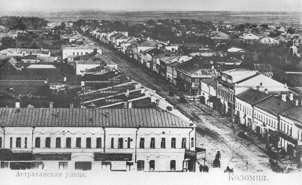 Schwarzes und weißes Foto einer Stadtstraße in Krasnoyarsk, Russland, mit Gebäuden, Bäumen und Menschen und einem Text am unteren Rand, der "Krasnoyarsk, die Hauptstadt von Russland" lautet.