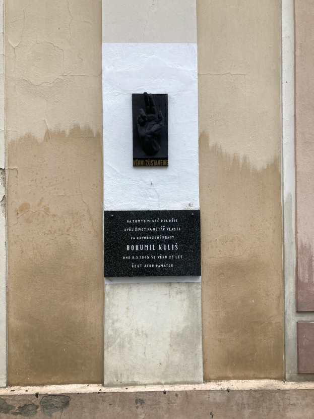 Eine schwarze Tafel an einem Gebäude mit einer darauf liegenden Hand, wahrscheinlich ein Mahnmal für Holocaust-Opfer.