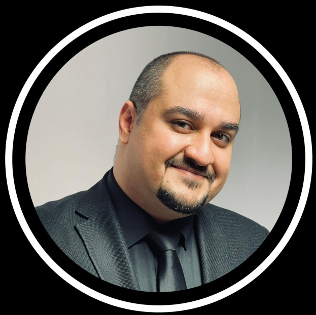 Ein Mann in Anzug und Krawatte mit einem freundlichen Gesichtsausdruck vor einem schwarzen Hintergrund, identifiziert als Anwalt in New York City.