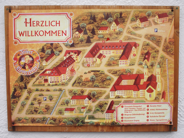 Ein detaillierter Stadtplan von Herzlich Willkommen, Deutschland, der an einer Gebäudewand angebracht ist und Straßen, Gebäude, Sehenswürdigkeiten und begleitenden Text zur Geschichte, Kultur und Attraktionen der Stadt zeigt.