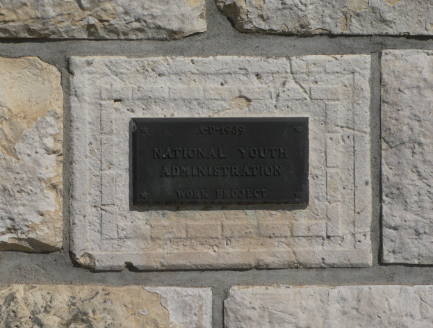 Steinwand mit einem rechteckigen Schild, auf dem "Nationales Jugendamt" in weißer, fetter Schrift auf schwarzem Hintergrund steht.