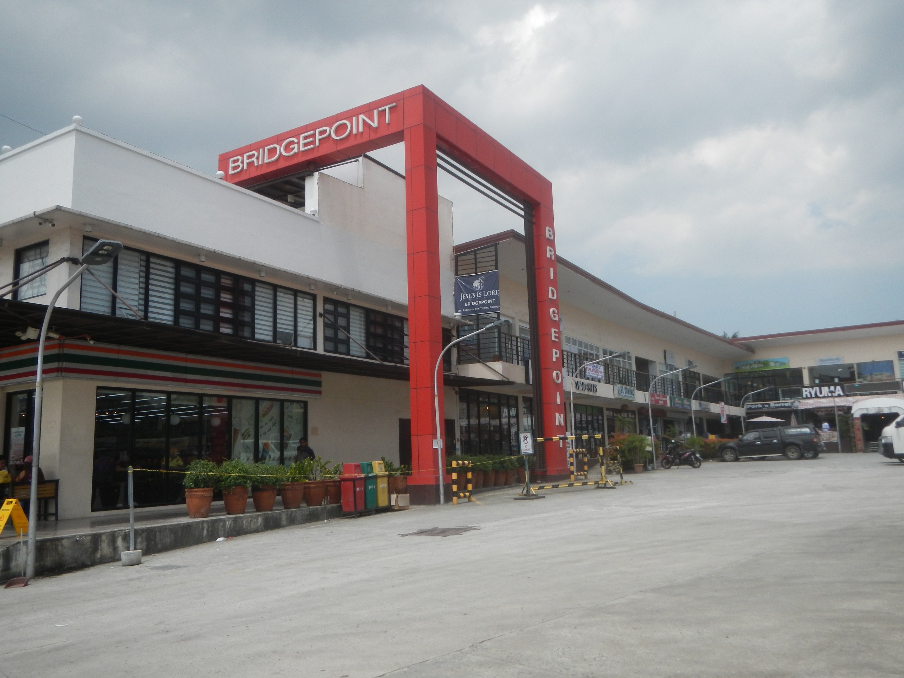Eine Bridgepoint-Tankstelle in den Philippinen mit umgebenen Infrastruktur, Fahrzeugen und Grünflächen unter einem bewölkten Himmel.