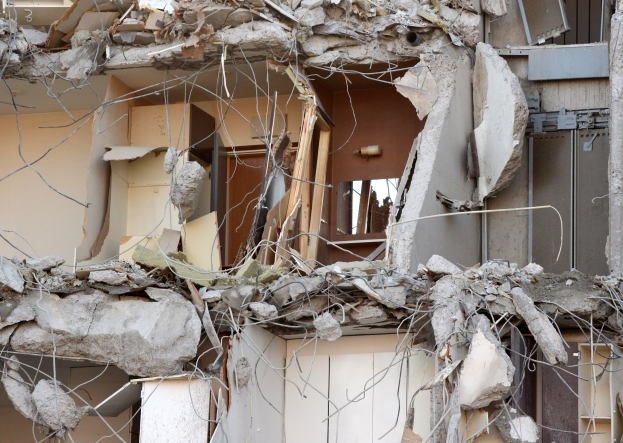 Teilweise abgerissener Bau mit gebrochenen Wänden und verstreutem Schutt, einschließlich Holz und Schutt.