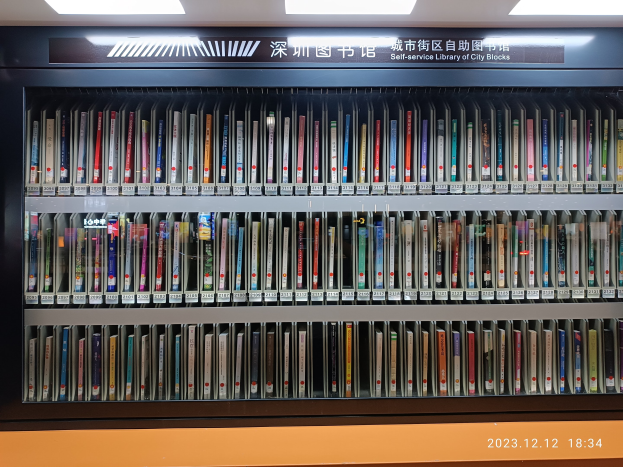 Eine gut beleuchtete Bibliothek mit hohen Bücherregalen voller Bücher, ein Schild mit Text und ein Wasserzeichen unten, das einer Selbstbedienungsbibliothek in Stadtblocks ähnelt.