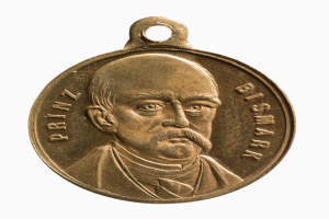 Eine goldene Medaille mit einem Porträt eines Schnauzbärtigen, darauf die Inschrift "Bismarck-Preis", vor einem weißen Hintergrund.