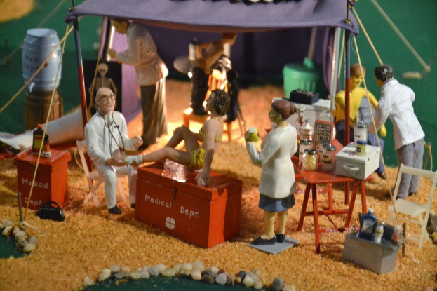 Eine Sammlung von Spielzeugen, die mit einem auf einer Box mit der Aufschrift "medizinisches Departement" angeordnet sind, ein Tisch in der rechten Ecke mit Gegenständen darunter ein violetter Zelt, mit zusätzlichen Gegenständen im Hintergrund.