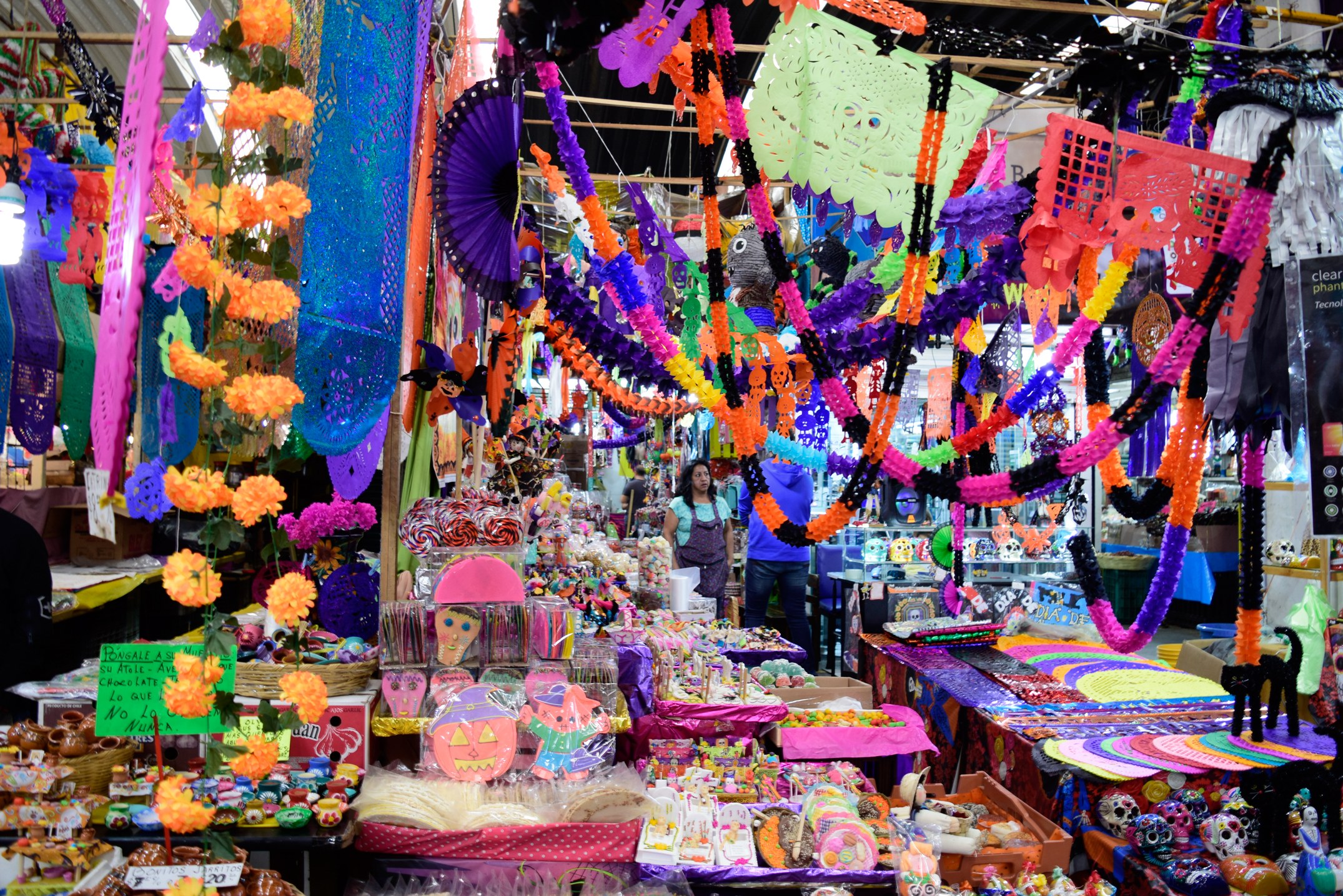 Ein belebter Markt mit Ständen, die Spielzeug, Dekorationsgegenstände und andere Gegenstände verkaufen, unter einer mit Lichtern geschmückten Decke, mit Menschen, die herumlaufen.