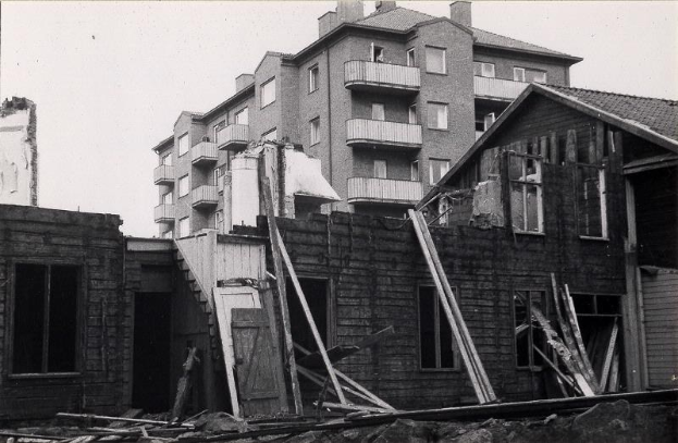 Schwarzes und weißes Foto eines abgerissenen West End Apartments-Gebäudes mit Schutt auf dem Boden und Himmel im Hintergrund.