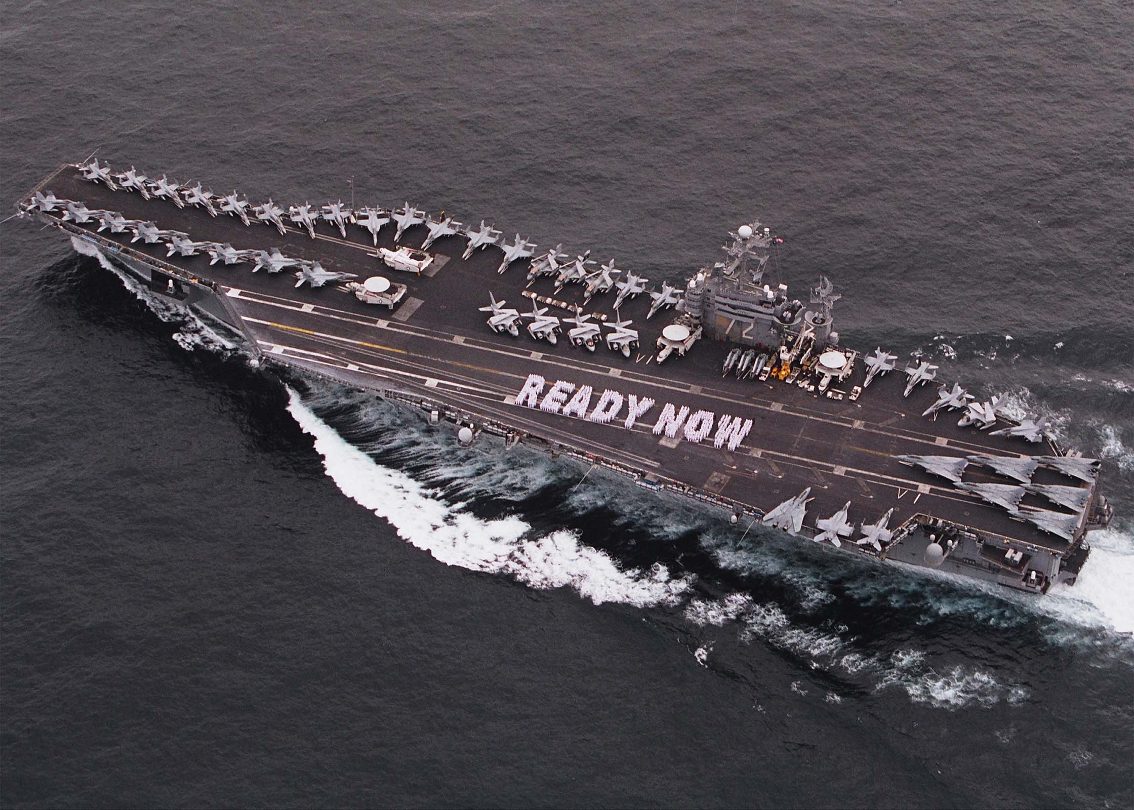 Flugzeugträger USS George H W Bush CVN-68 durchquert den Arabischen Meer mit Flugzeugen und Ausrüstung auf dem Deck, das 'Ready Now' auf der Seite zeigt.