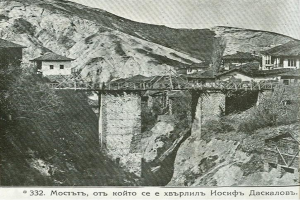 Ein altes Schwarz-Weiß-Foto einer Brücke über einen Fluss, mit Häusern auf beiden Seiten und einem Hügel im Hintergrund, mit dem Text "Mosambik - die Brücke des Flusses" unten.
