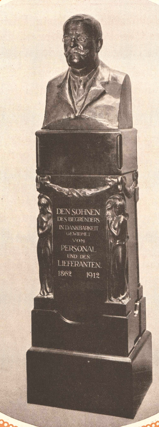 Schwarzes und weißes Foto einer Büste eines Mannes in Anzug und Krawatte, mit Inschrift, wahrscheinlich ein Gedenkdenkmal.