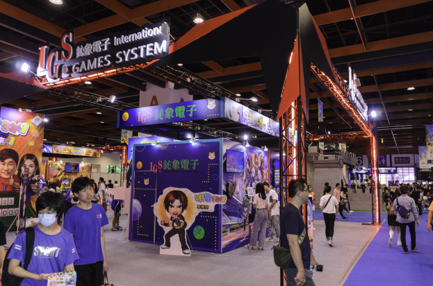 Eine Gruppe von Menschen geht durch einen Convention Hall auf einer Gaming-Messe in China, einige tragen Taschen und halten Gegenstände, mit Text- und Bildtafeln, Deckenlichtern und Teppichboden.