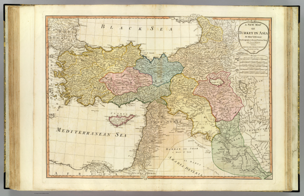 Offenes Buch mit detaillierter Karte von Türkei in Asien auf grauem Hintergrund, mit sichtbarem Text auf dem Papier.