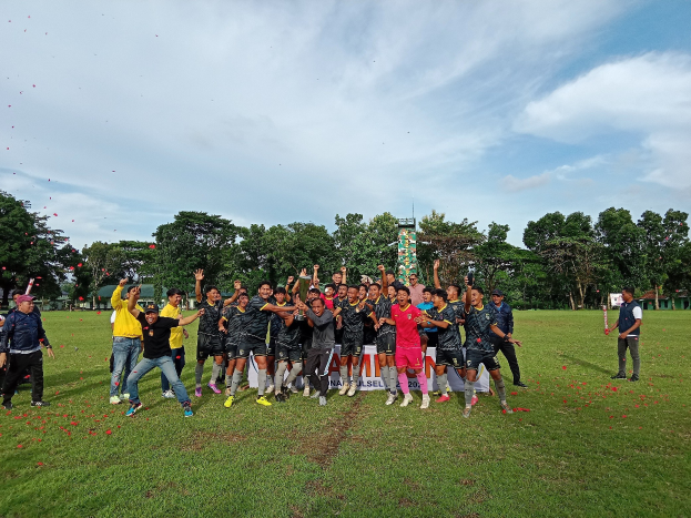 Gruppe von Menschen feiert auf einem grünen Feld mit einem "Cambodia Rugby World Cup 2019"-Schild im Hintergrund.