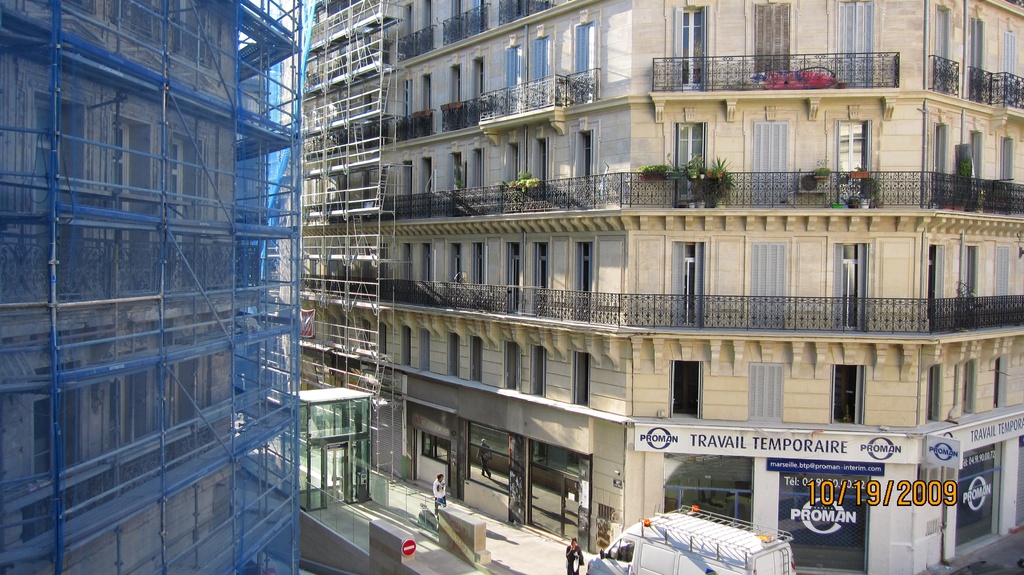 Ein großes Gebäude mit einem Geschäft im Erdgeschoss und Baumaßnahmen auf der linken Seite.