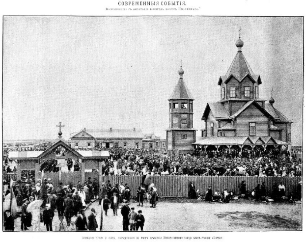 Schwarzer und weißer Fotografie einer Menge vor der Kirche der Interzession am Nerl mit einem hölzernen Zaun im Vordergrund und Gebäuden im Hintergrund.