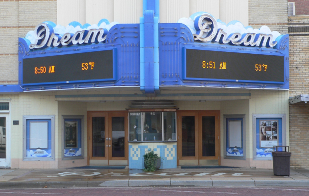 Außenansicht des Dream Theaters in St. Louis, Missouri, mit Glastüren, Fenstern, einem Namensschild, einem Müllcontainer, einem Topf mit einer Pflanze und einer Straße im Vordergrund.