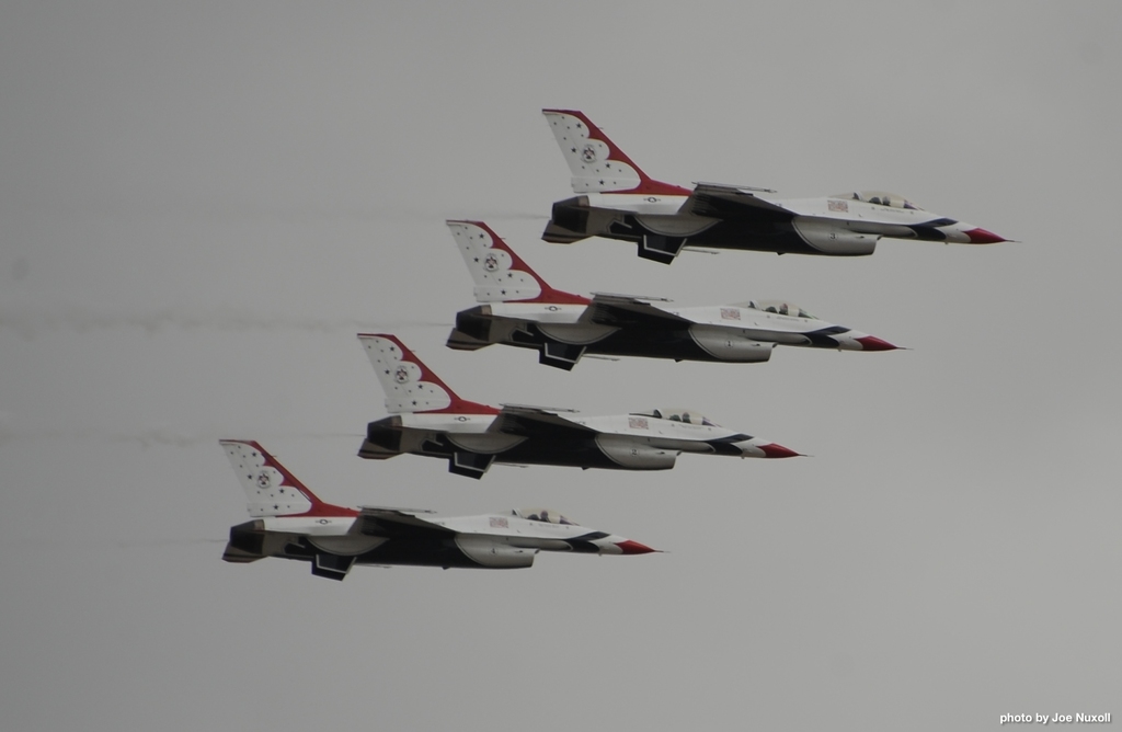 Vier Jets fliegen am Himmel mit einem Wasserzeichen in der rechten unteren Ecke.
