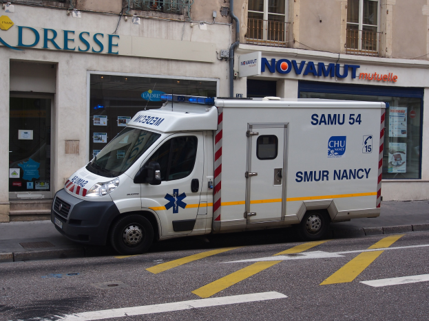 Ambulanz auf der Straßenseite vor einem Gebäude mit Krankenhausschild geparkt.