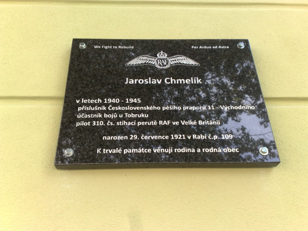 Schwarze Plakette mit weißer Schrift "Jaroslav Chmelik" an einer Gebäudewand angebracht, mit dekorativem Rahmen.