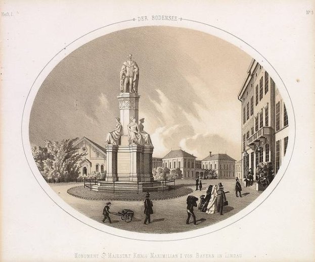 Schwarz-weiß-Zeichnung der Statue des Heiligen Majestrat König Maximilian I. von Bayern in einem Stadtplatz, umgeben von Gebäuden, Bäumen und Menschen, mit Text unten und Himmel im Hintergrund.