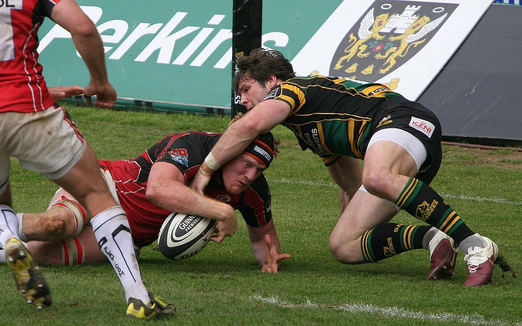 Eine Gruppe von Menschen auf dem Boden beim Spiel mit einem Rugby-Ball.
