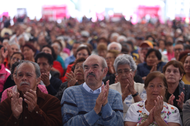 Eine große Gruppe von Menschen, die mit gefalteten Händen beten, vor einer Menge sitzend, mit einem unscharfen Hintergrund.
