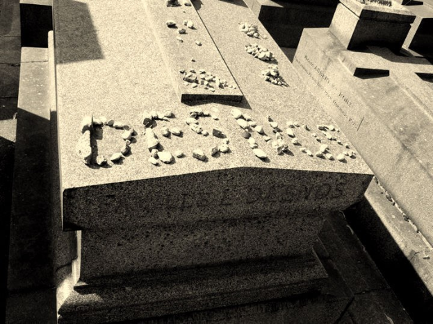 Schwarzes und weißes Foto eines Grabsteins mit der Inschrift 'Tod', umgeben von anderen Gräbern.