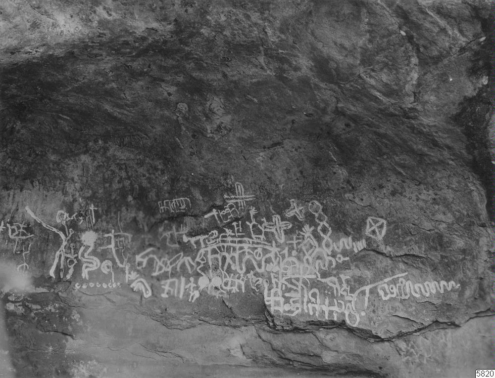 Schwarzes und weißes Foto eines Felsens mit farbenfrohem Graffiti in verschiedenen Formen.