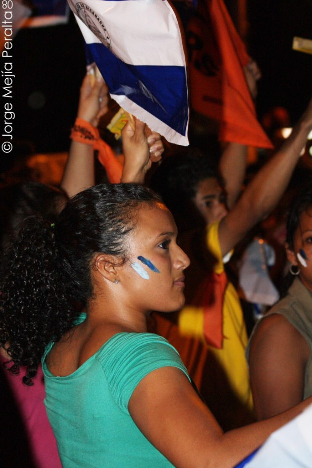 Frauen in grünen T-Shirts, die während einer Protestaktion weiße Decken halten.
