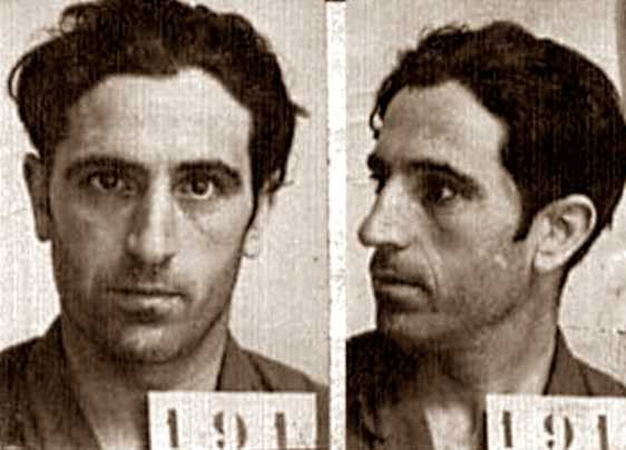 Schwarz-weißes Mugshot eines Mannes in einer Gefängniskleidung mit zwei nummerierten Bildern auf dem Papier, die angeblich der berüchtigte Serienkiller ist.