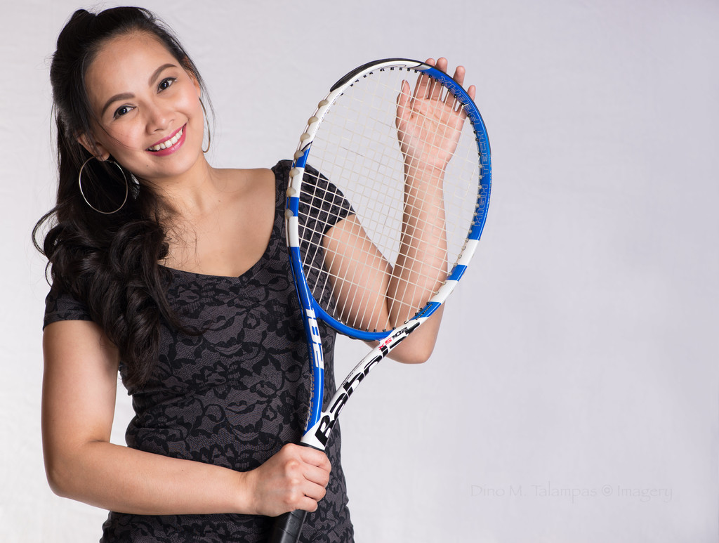 Eine Frau in einem schwarzen Kleid hält einen Shuttle-Schläger.