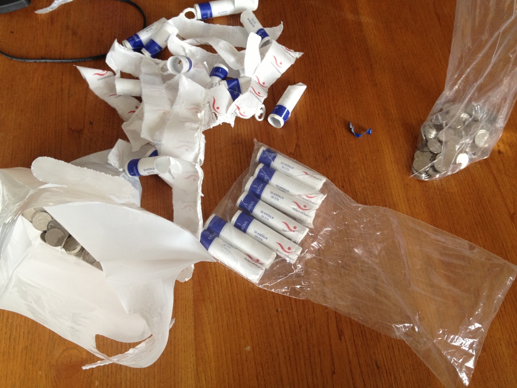 Weiße Objekte und Münzen werden auf einer hölzernen Oberfläche plaziert.