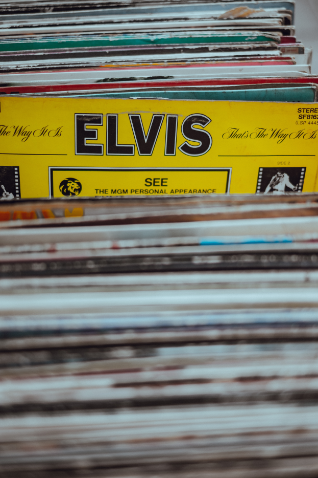 Ein ordentlicher Stapel Elvis-Presley-Platten auf einem Tisch, mit sichtbaren Titeln und einem unscharfen Hintergrund.