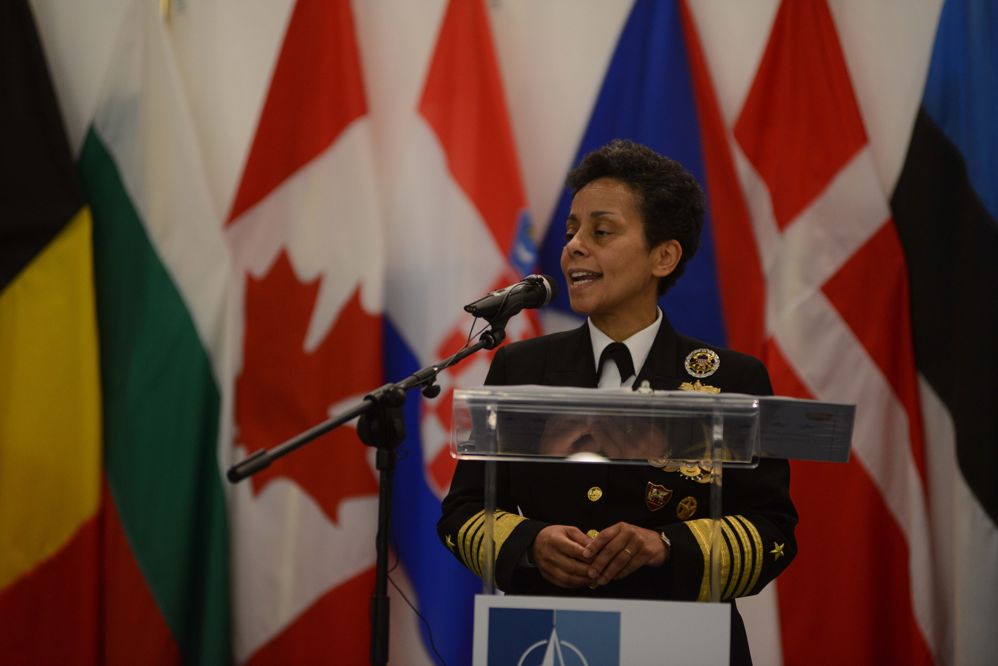 Frau in militärischer Uniform, identifiziert als UN-Generalsekretär, spricht an einem Rednerpult mit Mikrofon und einer Tafel, mit mehreren Flaggen im Hintergrund.