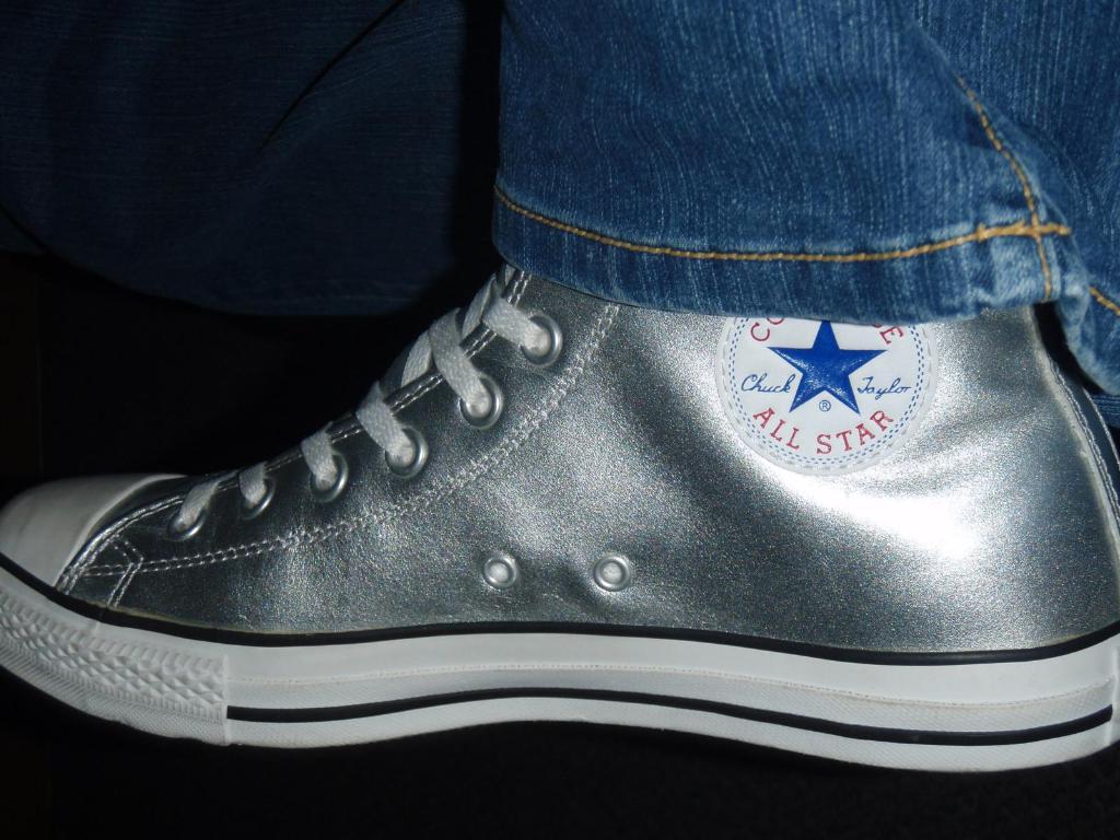 Ein Schuh mit Text und Schnürsenkeln, mit dem Rand von Jeans in der oberen rechten Ecke vor einem dunklen Hintergrund.