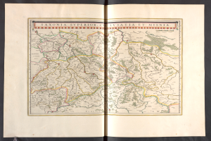 Ein aufgeschlagenes Buch mit einer detaillierten Karte von Sachsen, das seine Provinzen und Städte zeigt, vor schwarzem Hintergrund.