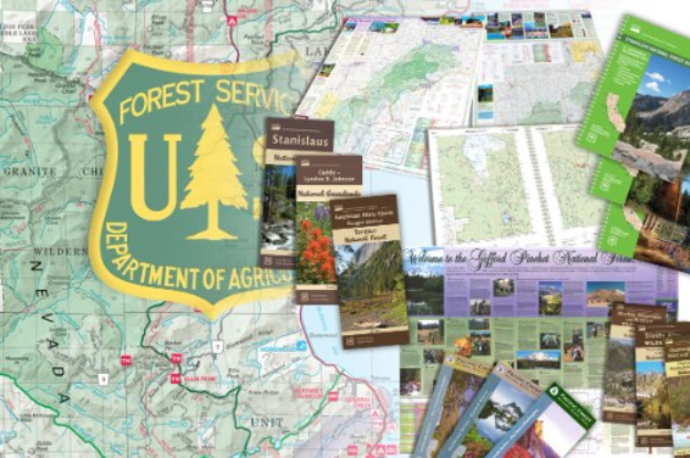 Eine Karte des United States Forest Service Department of Agriculture mit einem Schild-Logo mit einem Baum und dem Text "Forest Service", umgeben von verstreuten Büchern und Broschüren.