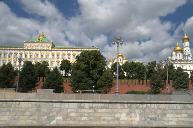 Erhabener Kreml in Moskau, Russland, mit ikonischen Gebäuden, Bäumen, Straßenlaternen, Straßenlaternen und einer umgebenden Wand unter einem bewölkten Himmel.
